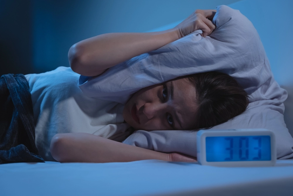Eine Frau liegt im Bett neben einem Wecker.